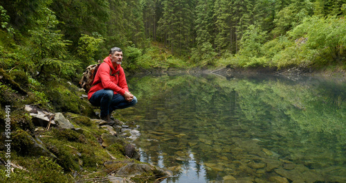 Bearded man with a backpack near a beautiful mountain lake