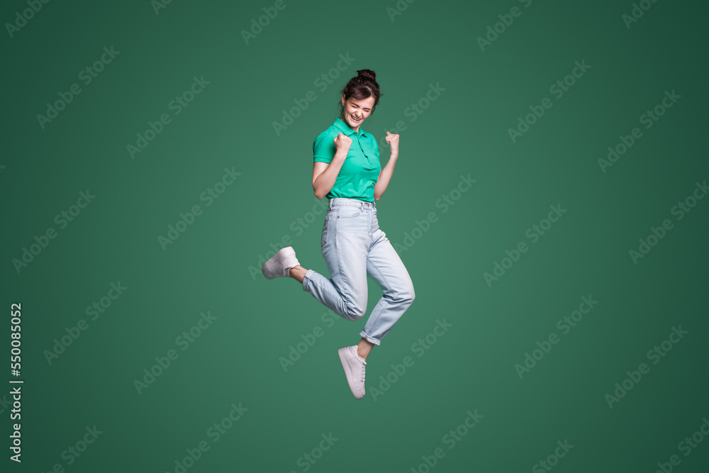 Full length portrait of attractive lovely pretty lucky girl celebrating success while jumping isolated over green background. Happiness, win, success. Full length portrait of attractive lovely pretty lucky girl celebrating success while jumping isolated over green background. Happiness, win, success.