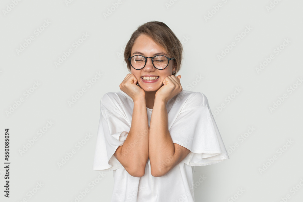 Casual cheerful woman with eyeglasses smiling at camera having fun with closed eyes while touch her face with hands isolated over white background. Fashion Casual cheerful woman with eyeglasses smiling at camera having fun with closed eyes while touch her face with hands isolated over white background. Fashion