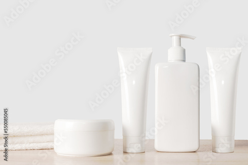 Shampoo cream and white dispenser with white towel. On a wooden background.