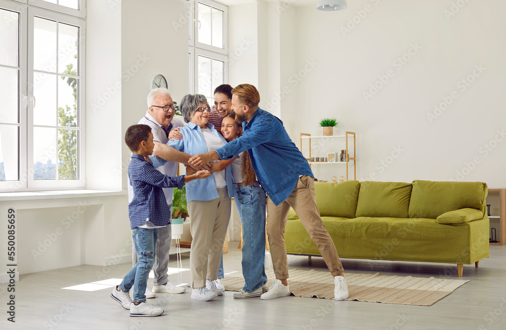 Happy large cute family hugging their beloved grandmother in a cozy bright spacious room at home. Concept of a dynasty in three generations, family ties, unconditional love, family relations, reunion. Happy large cute family hugging their beloved grandmother in a cozy bright spacious room at home. Concept of a dynasty in three generations, family ties, unconditional love, family relations, reunion.