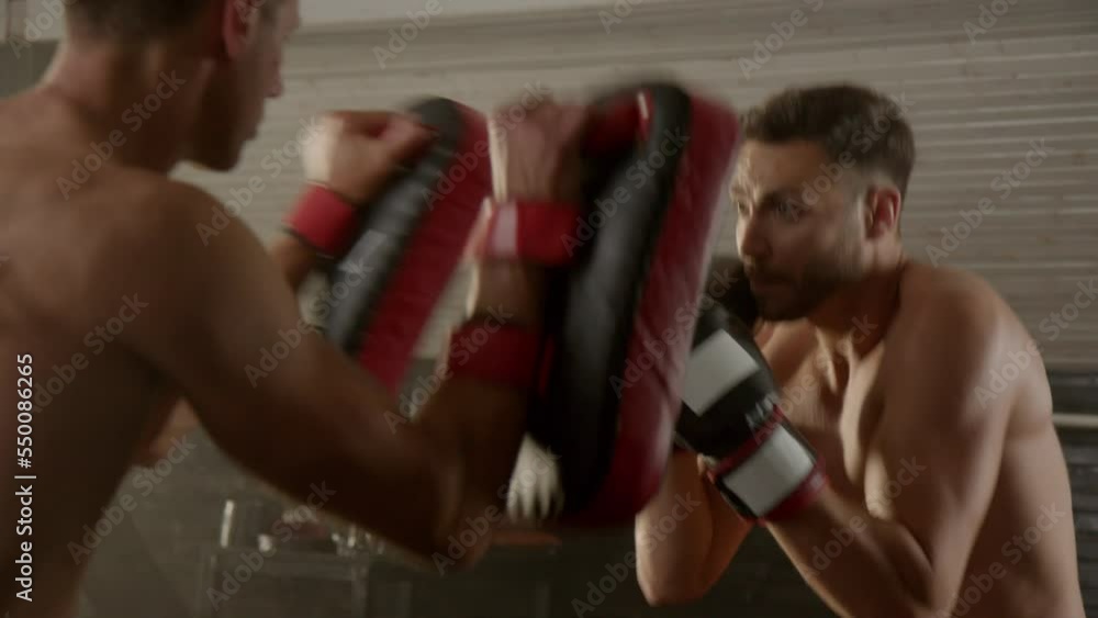 Young male boxer training punches in the gym with an instructor.Healthy lifestyle concept. Slow motion. Young male boxer training punches in the gym with an instructor.Healthy lifestyle concept. Slow motion.