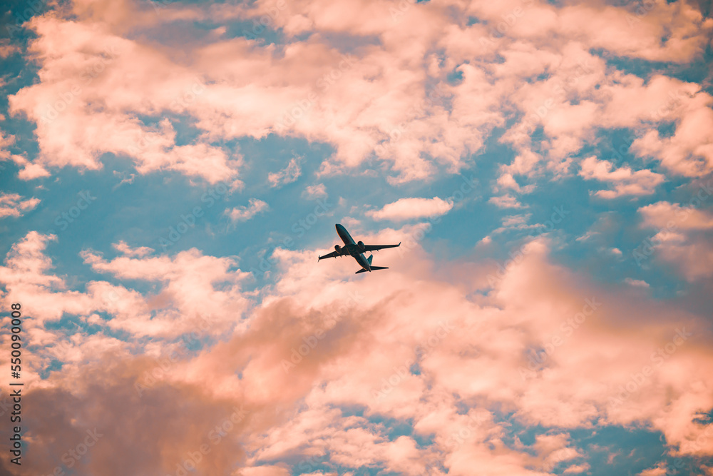 Naklejka premium Flugzeug beim starten mit einem wunderschönen Sonnenuntergang mit wunderbaren Farben im Himmel und an den Wolken