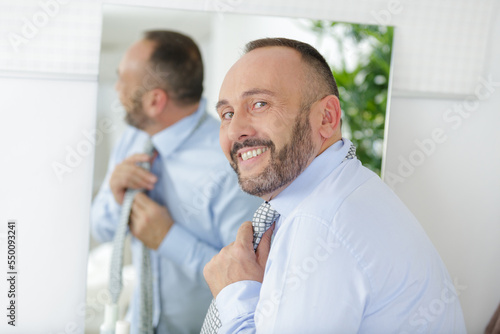 Canvas-taulu businessman straightening his tie in front of the mirror
