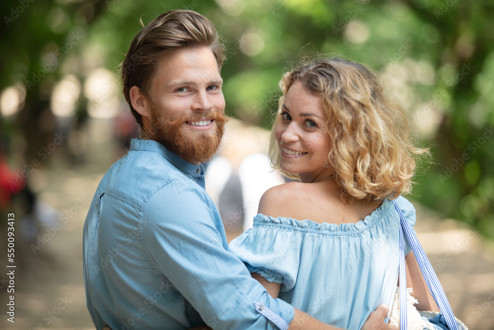 Fototapeta premium young woman and man walking in city park holding hands