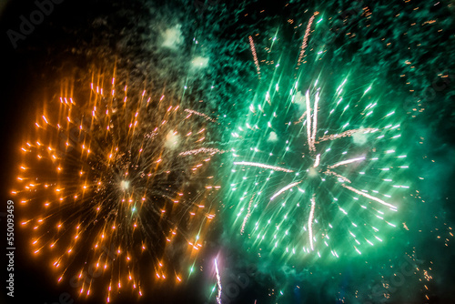 Green and yellow flashes fireworks explode in the sky