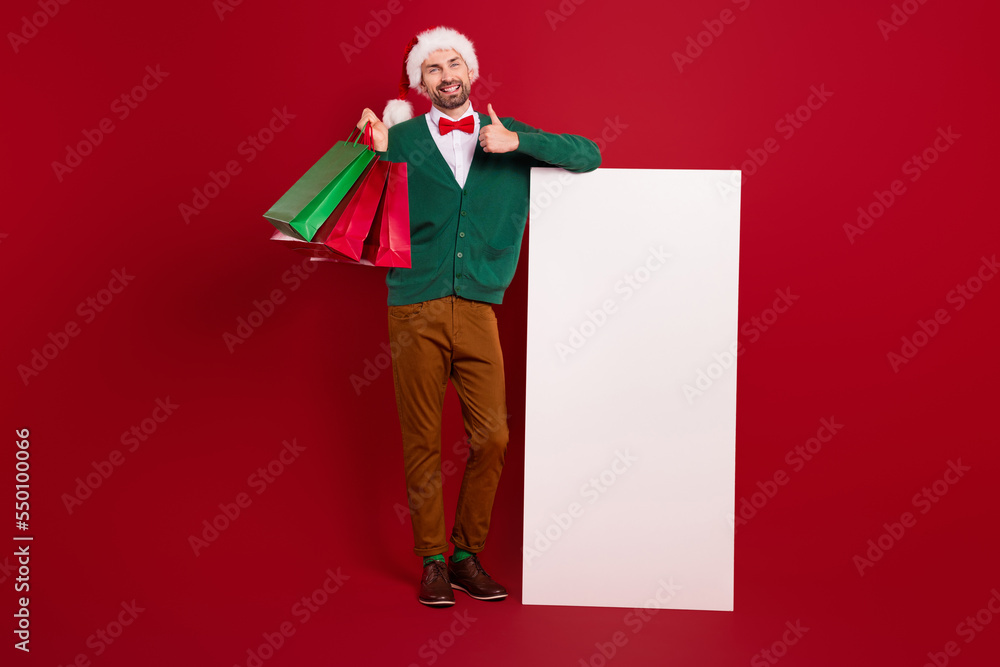 Full body portrait of elegant gentleman hold packages show thumb up huge empty space electronic panel isolated on red color background