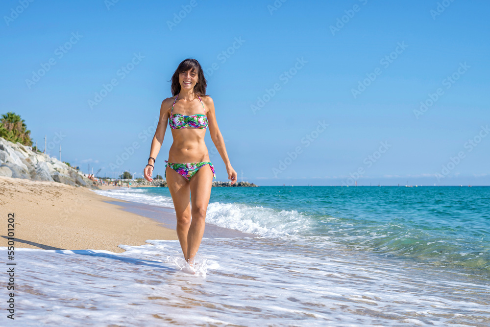 Front view of beautiful smiling woman in swinsuit walking on beach Front view of beautiful smiling woman in swinsuit walking on beach