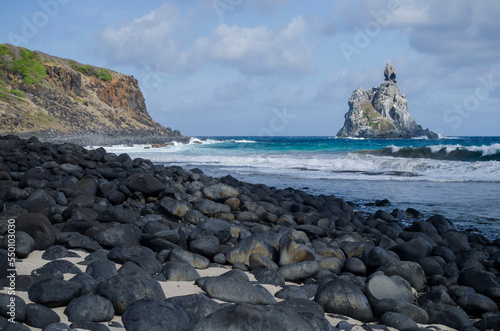 Scenery with pebbles at Atalaia Beach with rock formation in sea in distance photo