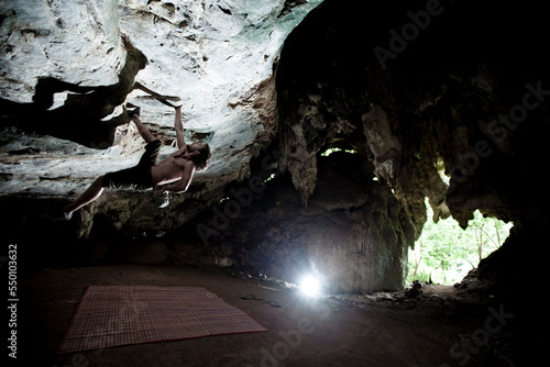 Caucasian male listening to MP3 player and climbing alone in a limestone cave in Thailand. photo
