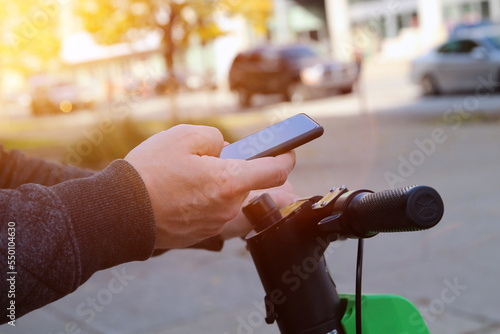 Close up image of a man on an electric scooter paying online by mobile phone