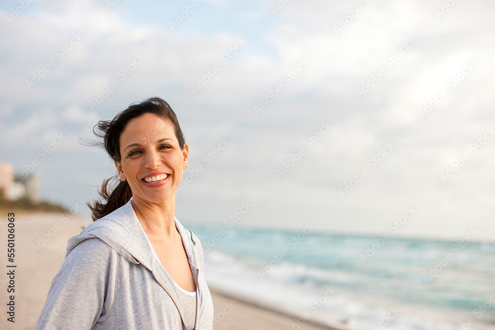 A hispanic woman wearing a sweatshirt relaxes during an early morning walk on the beach. A hispanic woman wearing a sweatshirt relaxes during an early morning walk on the beach.