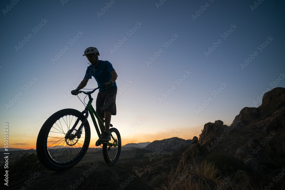 A man performs trial bike standing on a rock at El Diente, Jalisco, Mexico. A man performs trial bike standing on a rock at El Diente, Jalisco, Mexico.