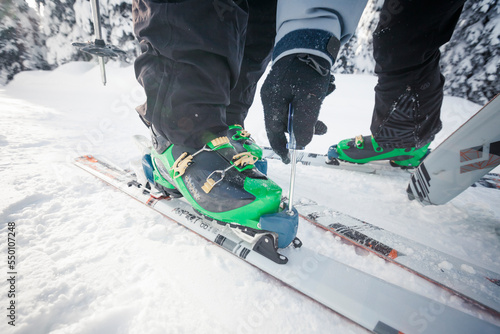 A backcountry skier uses a screw driver to set the DIN setting on his partners binding.