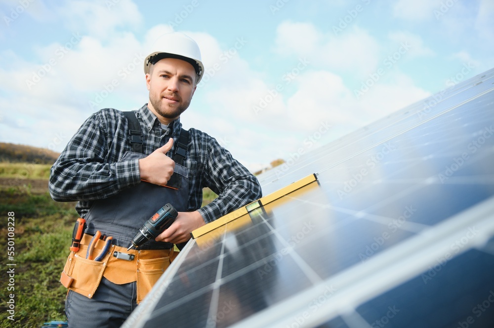 Male worker in uniform outdoors with solar batteries at sunny day. Male worker in uniform outdoors with solar batteries at sunny day.