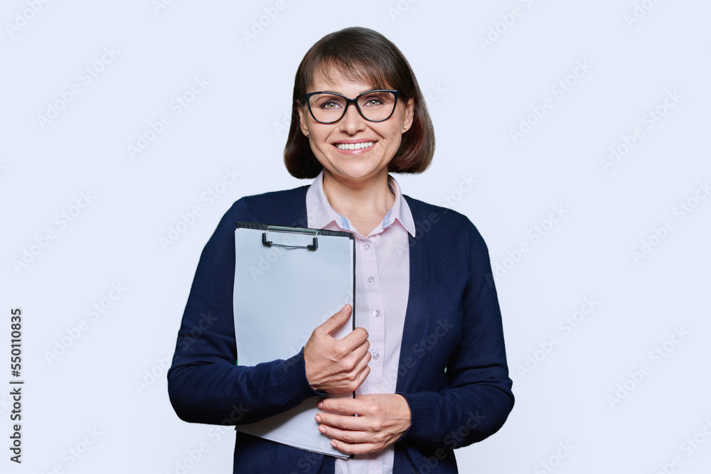 Middle age business woman with clipboard looking at camera on white background Middle age business woman with clipboard looking at camera on white background