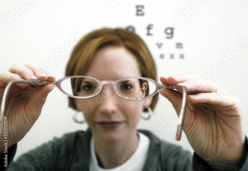 An optometrist putting a pair of glasses on for a patient. photo