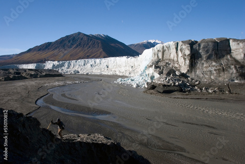 A hiker climbs a hill near the steep face of the Donjek Glacier, Kluane National Park, Yukon Territory. photo