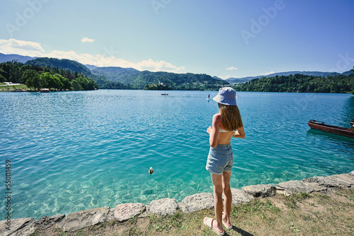 Back of teen girl in panama stand in pier of view beautiful Bled Lake, Slovenia. © AS Photo Family