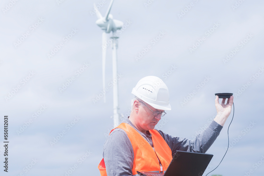 older energy engineer in front of a windmill older energy engineer in front of a windmill