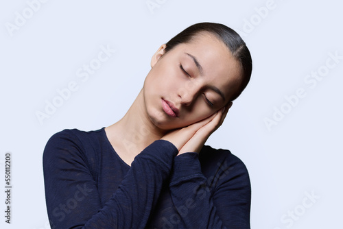 Young woman sleeping with closed eyes, on white studio background