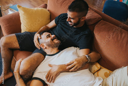 boy lying on his boyfriend on the sofa. they look happy photo