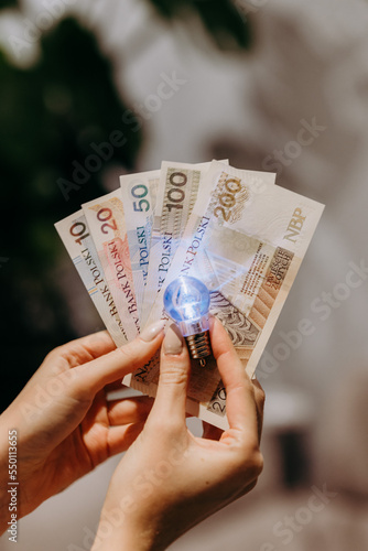 Zapalona żarówka na tle banknotów polskich