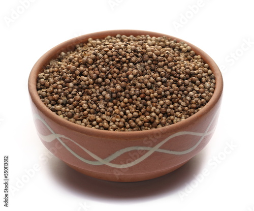 Pile coriander seeds in clay pot isolated on white 