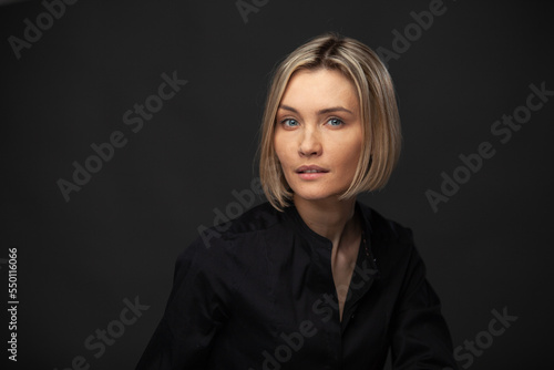 Beautiful middle-aged woman on a gray background in a black blouse.