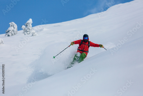 Extreme downhill skiing on a steep slope with snow spraying
