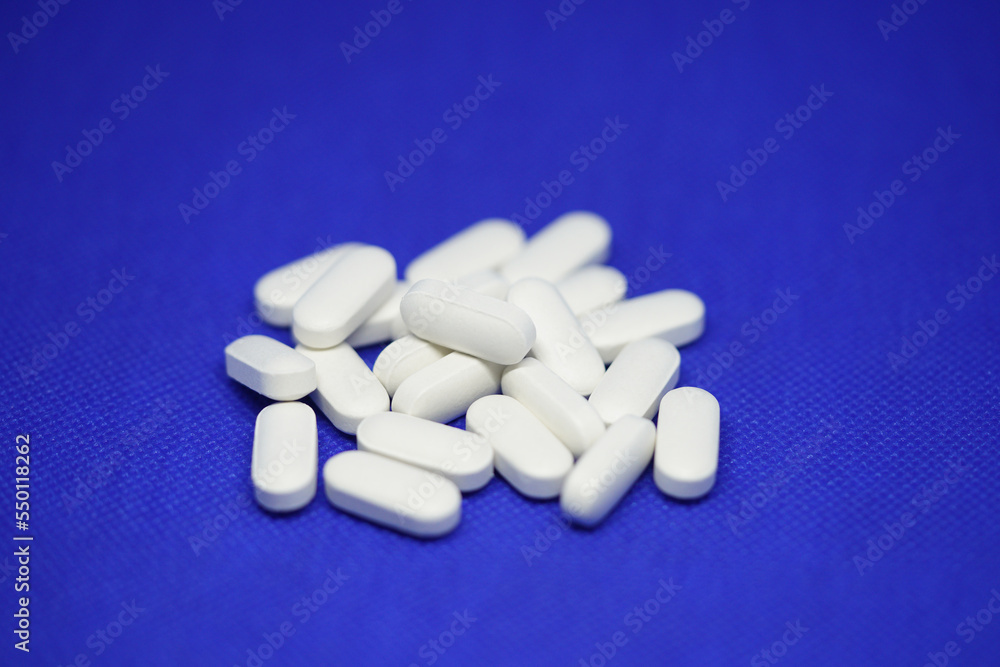 Heap of medical white pills on a blue background Heap of medical white pills on a blue background