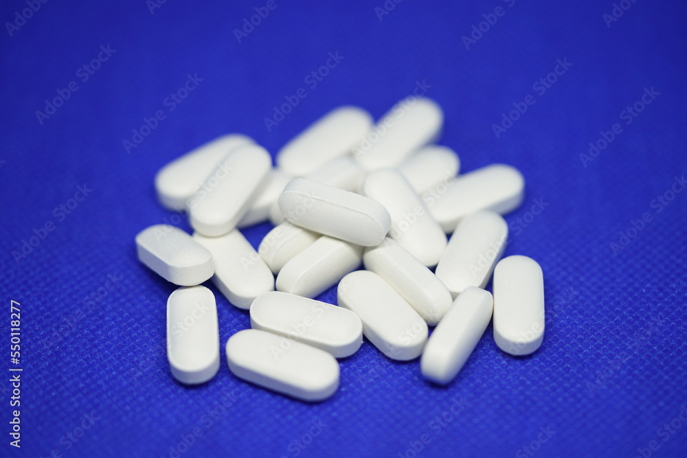 Heap of medical white pills on a blue background Heap of medical white pills on a blue background