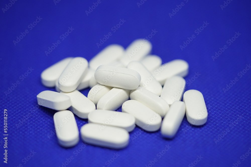 Heap of medical white pills on a blue background