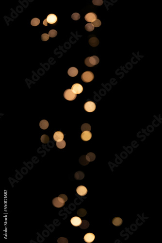 Blurred lights festive garland on a black background. Bokeh golden lights