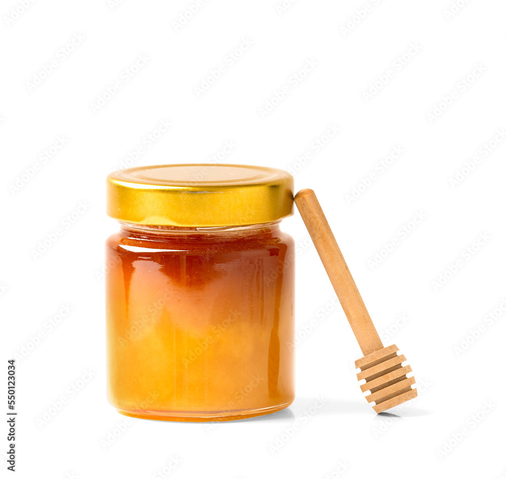 Fresh honey in a jar with a wooden dipper on a white isolated background.