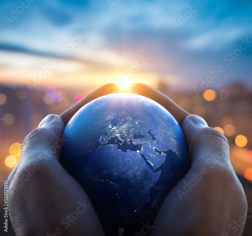 The globe Earth in the hands of man against the night city. Concept on business, politics, ecology and religion. Earth day abstract background. Elements of this image furnished by NASA.