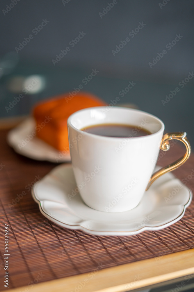 coffee and orange cake on a black background and porcelain tableware on a brown tapere