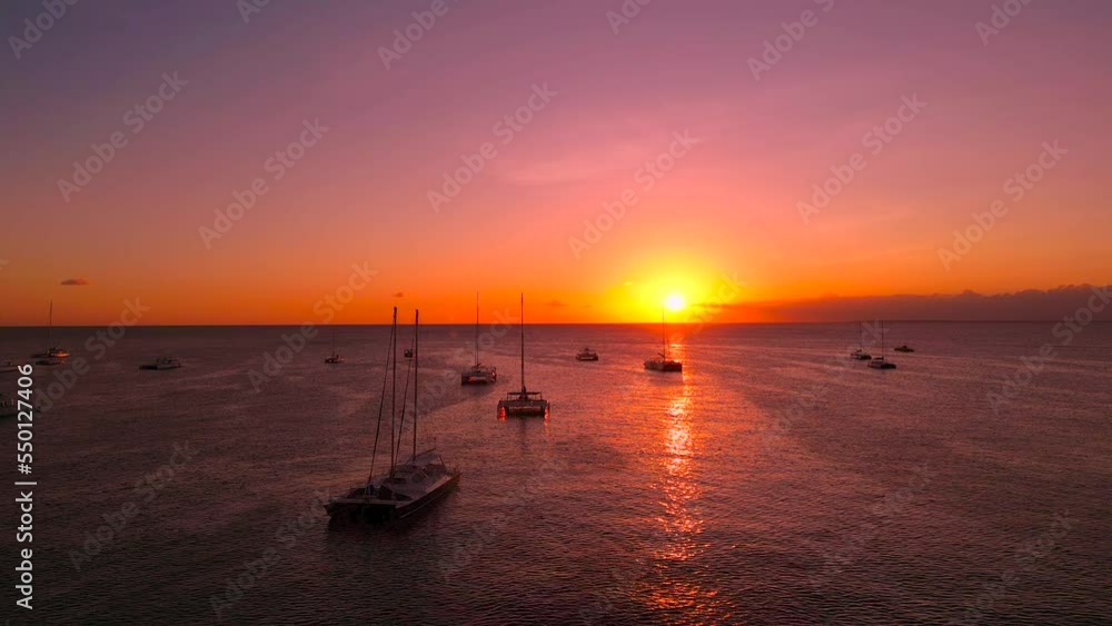 Amazing sunset in the Bayahibe port. Many moored at anchor sailing tourist yachts and catamarans. The sun sets over the horizon against pink sky Amazing sunset in the Bayahibe port. Many moored at anchor sailing tourist yachts and catamarans. The sun sets over the horizon against pink sky