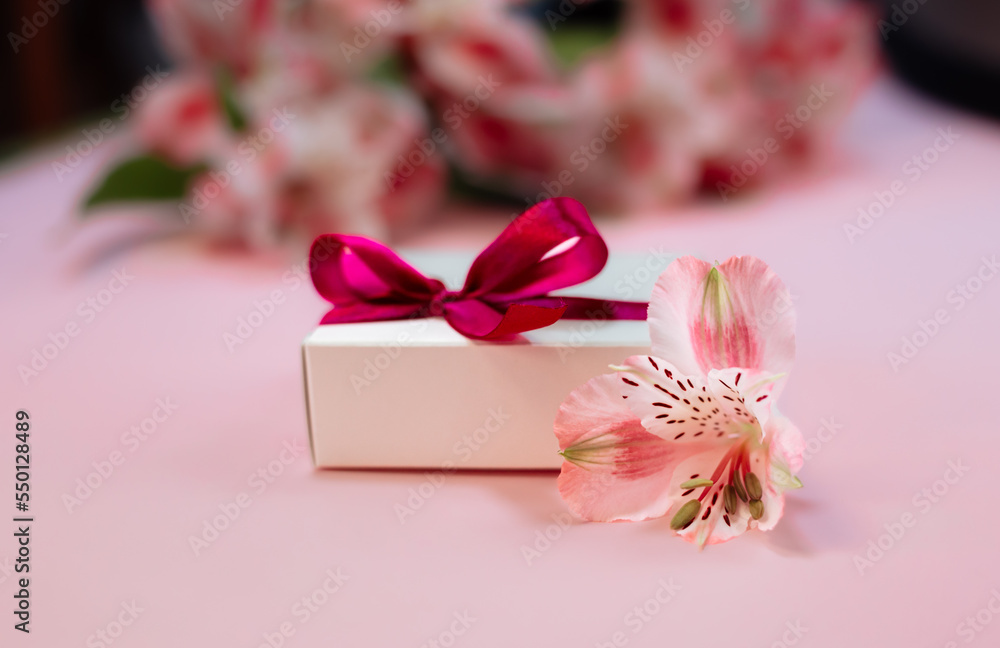 bouquet of red alstroemeria flowers background.  Flower card and white gift box with ribbon close up. Romantic present design.