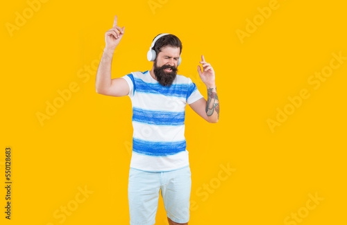 hipster man listen music in earphones isolated on yellow. pointing fingers. man in hipster earphones © be free