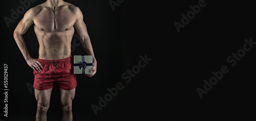 man with muscular torso hold holiday present. muscular man with holiday present. present from man © be free