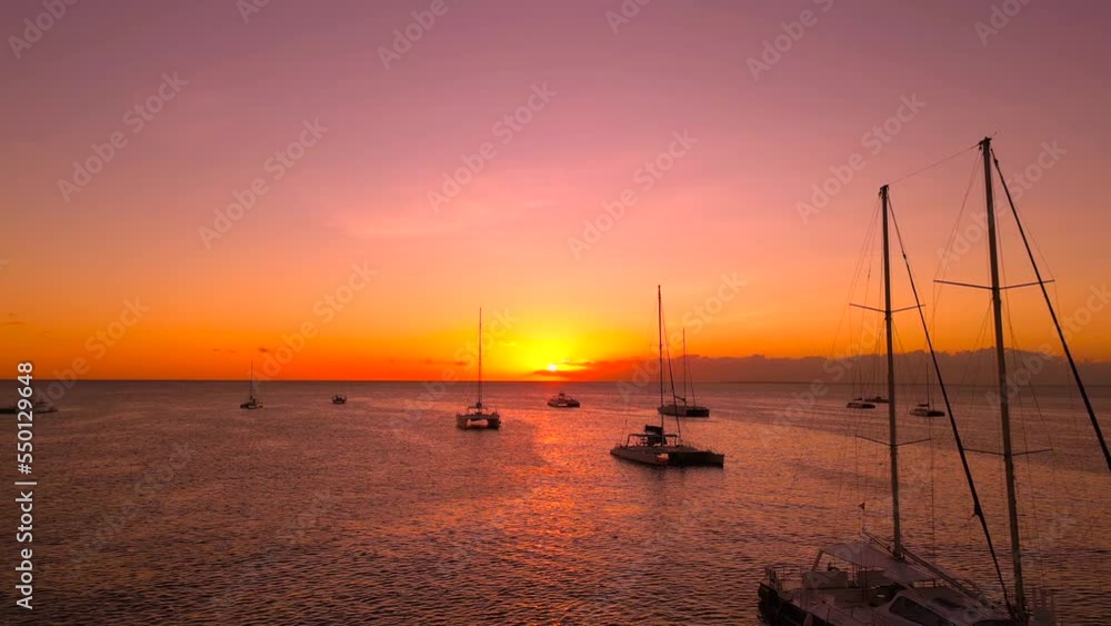 Aerial flight through moored at anchor sailing tourist yachts and catamarans with high mast at amazing pink sunset. Beautiful nautical seascape Aerial flight through moored at anchor sailing tourist yachts and catamarans with high mast at amazing pink sunset. Beautiful nautical seascape