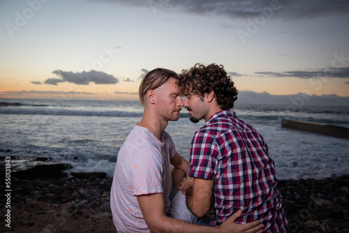 Two lovers having a romantic moment at the beach during sunset, same-sex couple on vacation.
