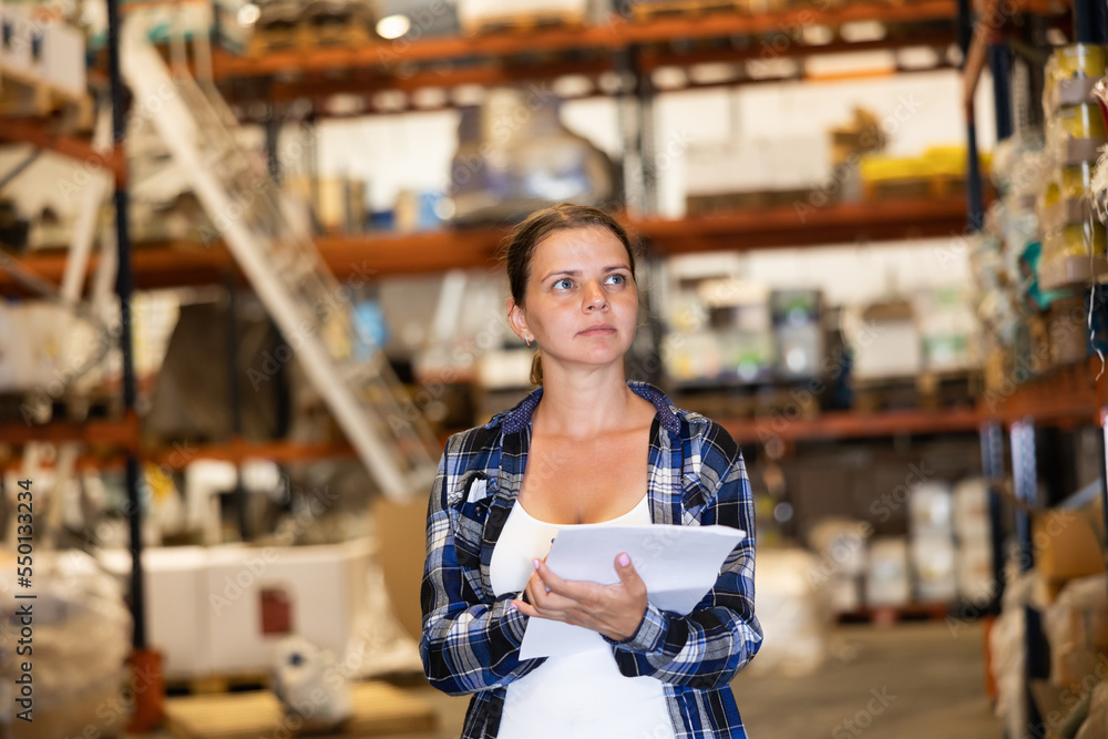 Female manager leads the accounting of materials in a large warehouse
