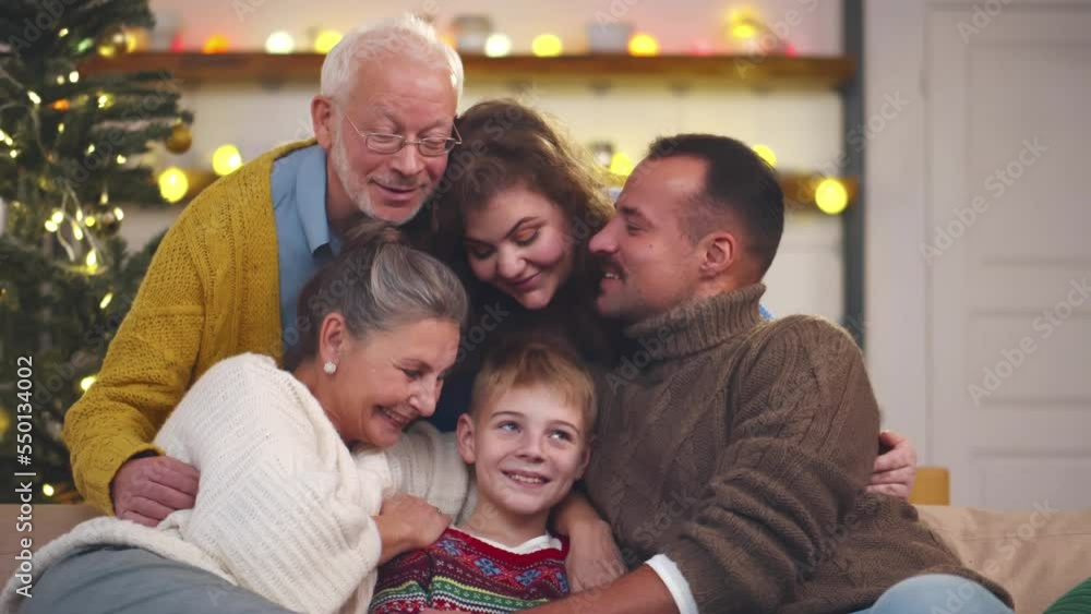 Three generation family sitting on couch and hugging celebrating Christmas together. Realtime Three generation family sitting on couch and hugging celebrating Christmas together. Realtime