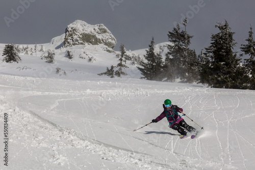 Female skier skiing downhill during sunny day in high mountains