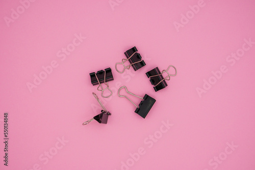 An image of black paper clips on pink background