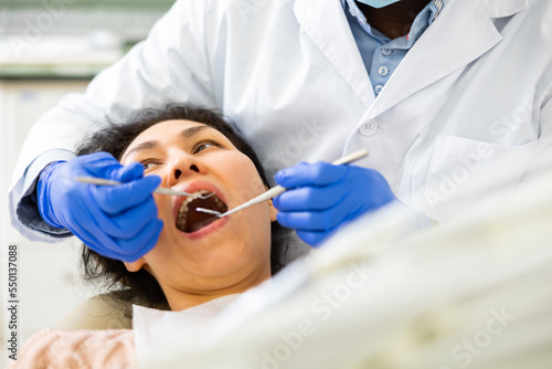 Asian woman sitting on dental chair with opened mouth and waiting for medical procedures ending in dentistry clinic.