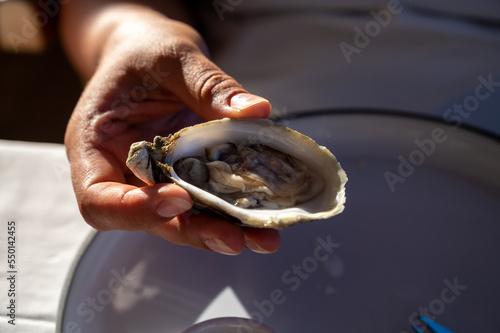 Young woman in white dress eats fresh live oysters seafood in French restaurant