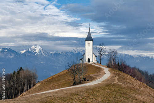 Church on top of a hill in front of mountains at Jamnik in Slovenia